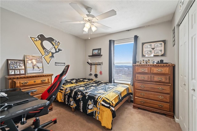 bedroom featuring a closet, a textured ceiling, light carpet, and a ceiling fan