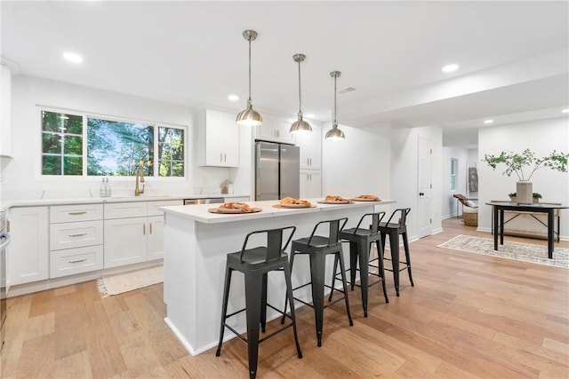 kitchen featuring a breakfast bar area, a center island, light wood-type flooring, and stainless steel appliances