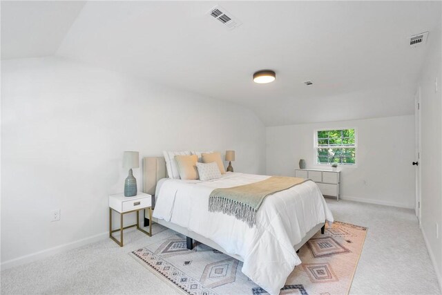 bedroom with visible vents, light colored carpet, baseboards, and vaulted ceiling