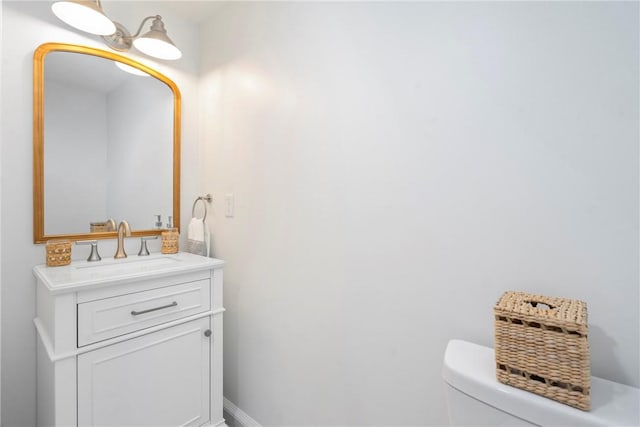 bathroom with baseboards, toilet, and vanity