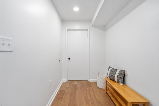 corridor with light wood-type flooring and baseboards