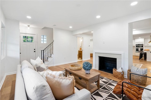 living area featuring light wood-style flooring, recessed lighting, and stairs