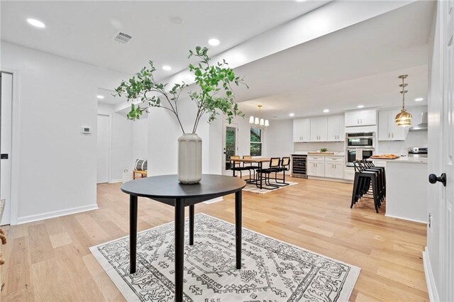 dining space with light wood finished floors, visible vents, wine cooler, and recessed lighting