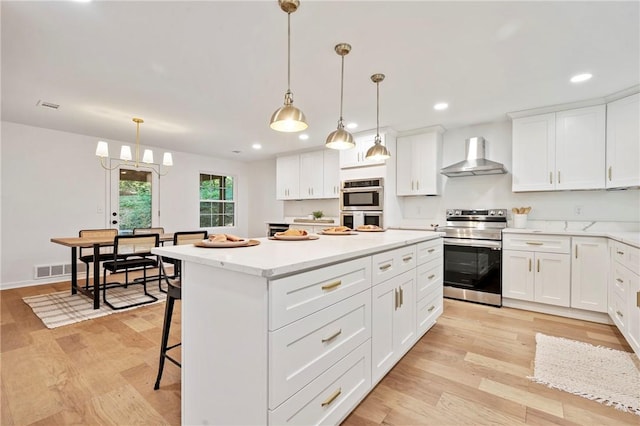 kitchen with a kitchen island, white cabinetry, recessed lighting, appliances with stainless steel finishes, and wall chimney range hood