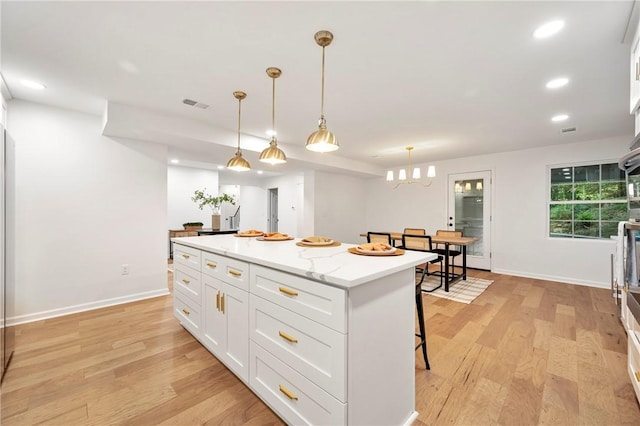 kitchen featuring a breakfast bar area, visible vents, white cabinets, and a kitchen island