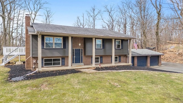 raised ranch with driveway, a front lawn, a garage, brick siding, and a chimney