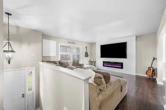 living area featuring a glass covered fireplace, dark wood-style floors, and baseboards