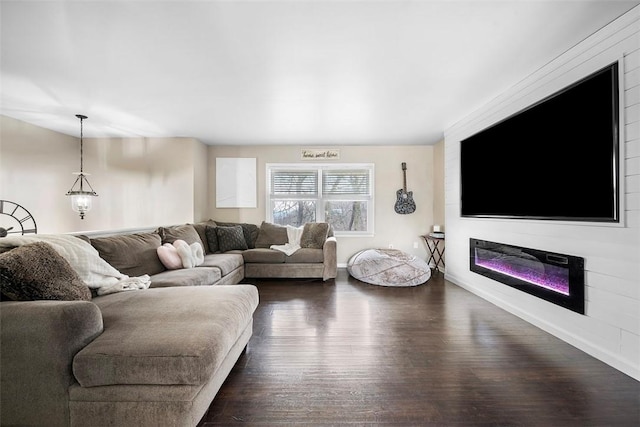 living room with a glass covered fireplace, baseboards, and dark wood-style flooring