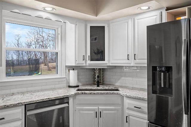 kitchen with decorative backsplash, appliances with stainless steel finishes, white cabinetry, and a sink