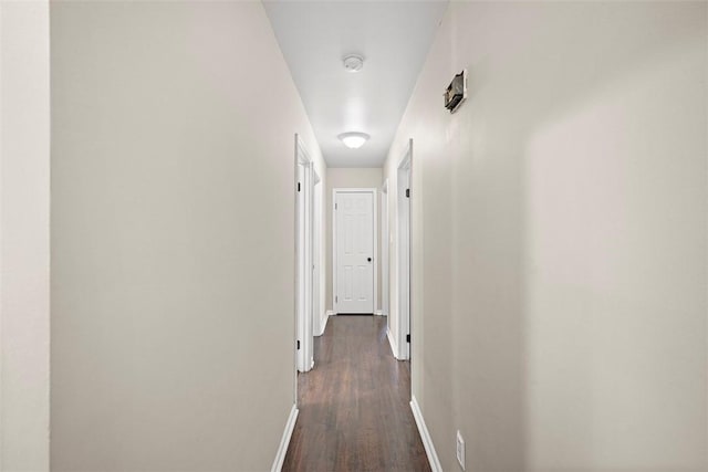 hallway with dark wood finished floors and baseboards