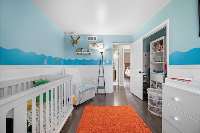 bedroom featuring visible vents, wood finished floors, and a wainscoted wall