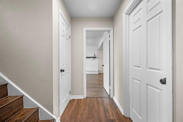 corridor with stairs, baseboards, and dark wood-style flooring