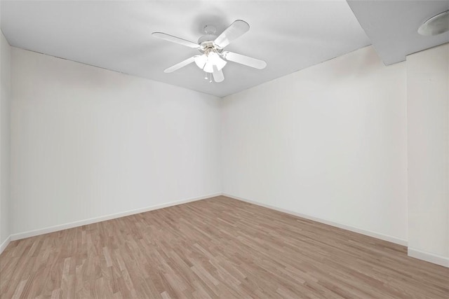 empty room with ceiling fan, light wood-type flooring, and baseboards