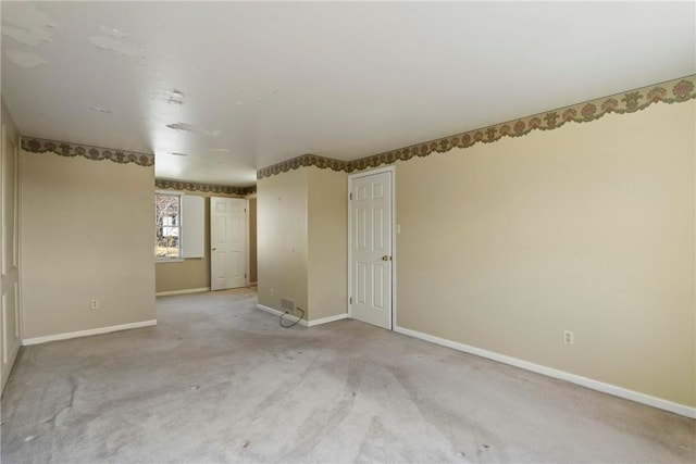 spare room featuring baseboards and light carpet