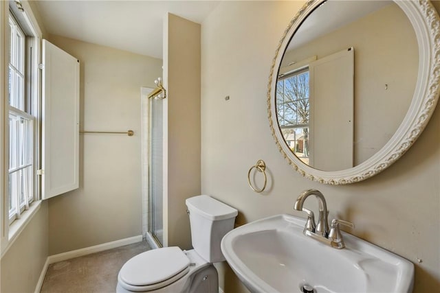 bathroom with a sink, baseboards, toilet, and a shower stall