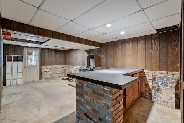 bar with wooden walls, concrete flooring, brick wall, and a paneled ceiling