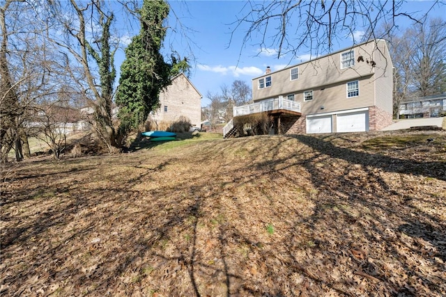 back of house with stairway, a garage, and a chimney