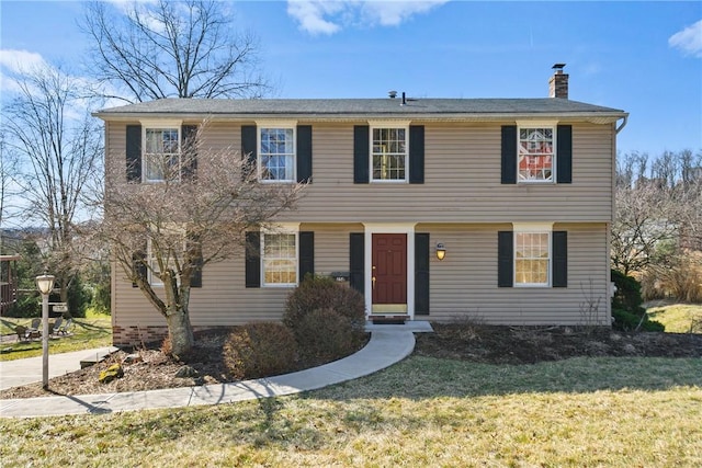 colonial-style house with a front lawn and a chimney