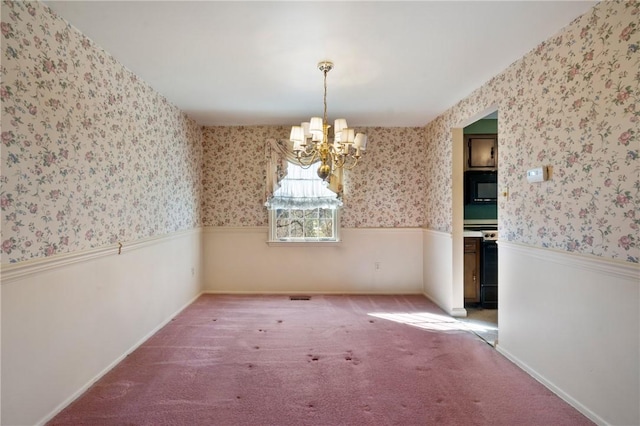 unfurnished dining area with wallpapered walls, carpet flooring, a wainscoted wall, and a chandelier