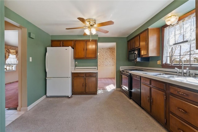 kitchen with a wealth of natural light, light carpet, black appliances, and a sink