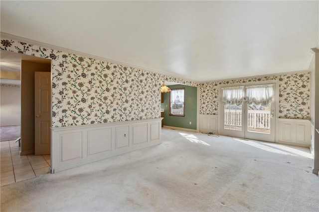 spare room featuring a wainscoted wall, carpet flooring, wallpapered walls, and ornamental molding