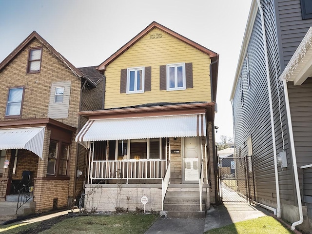 view of front of house featuring brick siding, covered porch, and a gate