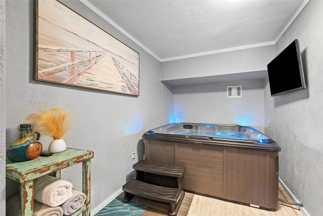 miscellaneous room featuring a hot tub, crown molding, baseboards, wood finished floors, and a textured wall