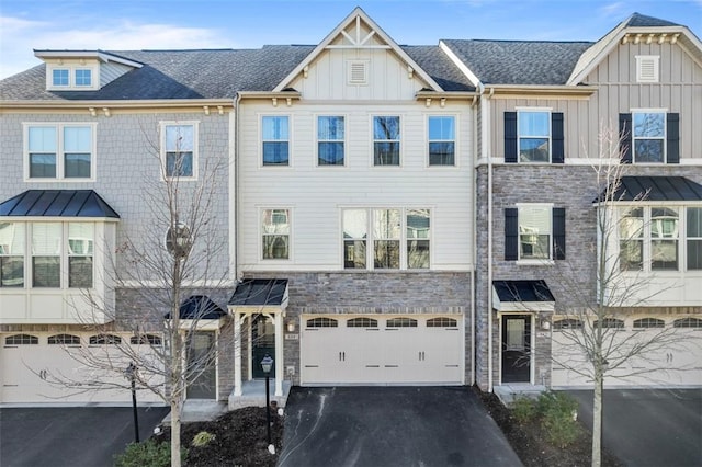 townhome / multi-family property featuring driveway, stone siding, roof with shingles, board and batten siding, and a garage