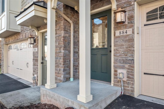 doorway to property featuring stone siding, covered porch, and a garage