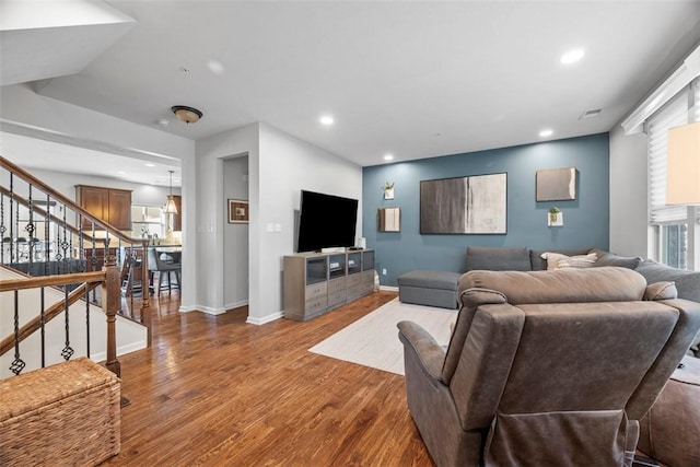 living area with stairway, wood finished floors, visible vents, baseboards, and recessed lighting