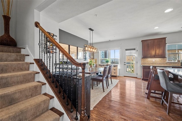 dining space with wood finished floors, baseboards, recessed lighting, stairs, and a chandelier