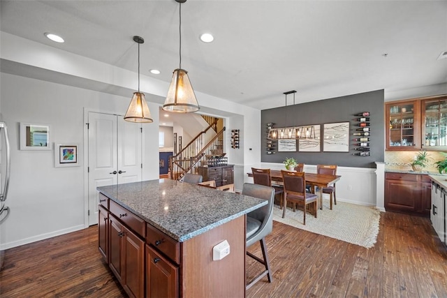 kitchen with recessed lighting, glass insert cabinets, a kitchen breakfast bar, and dark wood-type flooring