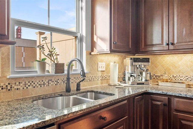 kitchen featuring decorative backsplash, light stone counters, plenty of natural light, and a sink