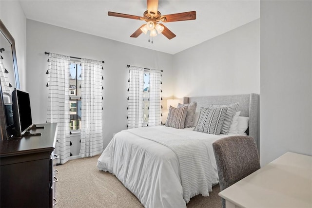 bedroom featuring light colored carpet, a ceiling fan, and multiple windows