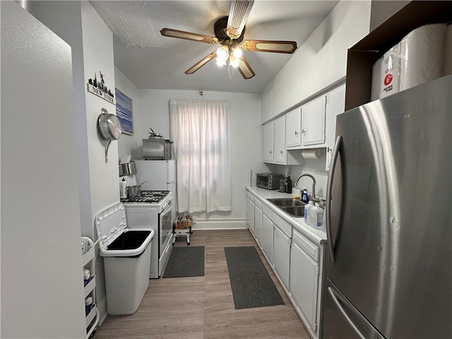 kitchen with gas range gas stove, freestanding refrigerator, a sink, light countertops, and white cabinetry