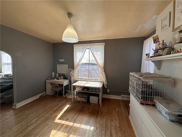 interior space featuring baseboards, arched walkways, and wood finished floors