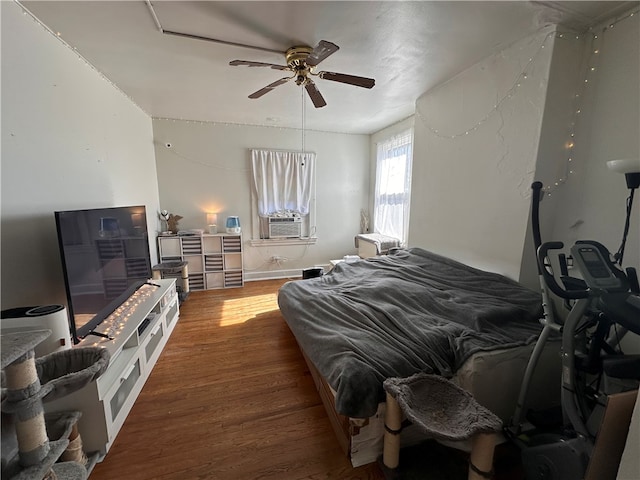 bedroom with cooling unit, ceiling fan, and wood finished floors