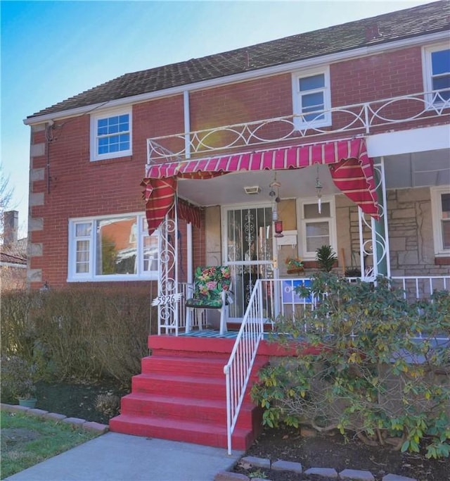 multi unit property with a porch and brick siding