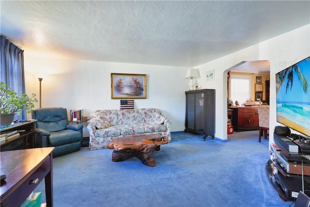 carpeted living area featuring arched walkways and a textured ceiling