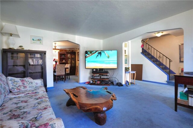 carpeted living room featuring stairs, arched walkways, and a textured ceiling