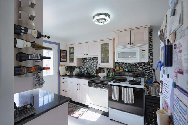 kitchen featuring dark countertops, range with electric stovetop, decorative backsplash, white microwave, and dishwasher