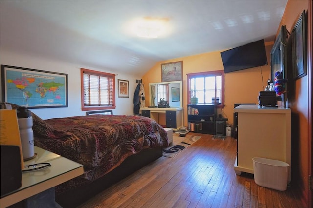 bedroom with multiple windows, lofted ceiling, and hardwood / wood-style flooring