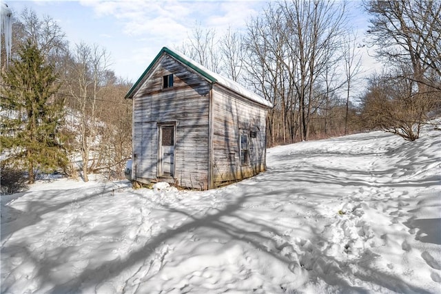 snow covered structure with an outbuilding