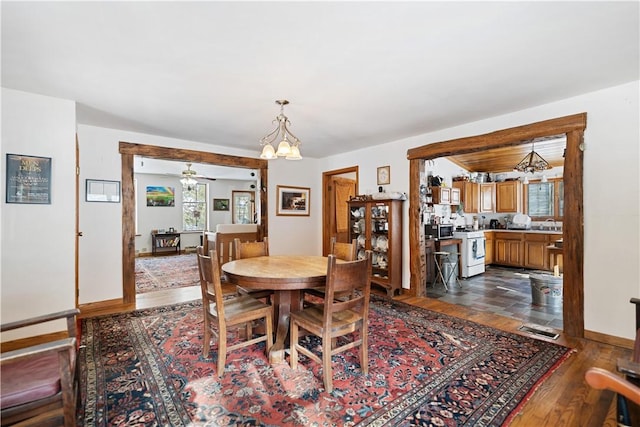 dining room featuring ceiling fan with notable chandelier, visible vents, dark wood-style floors, and baseboards