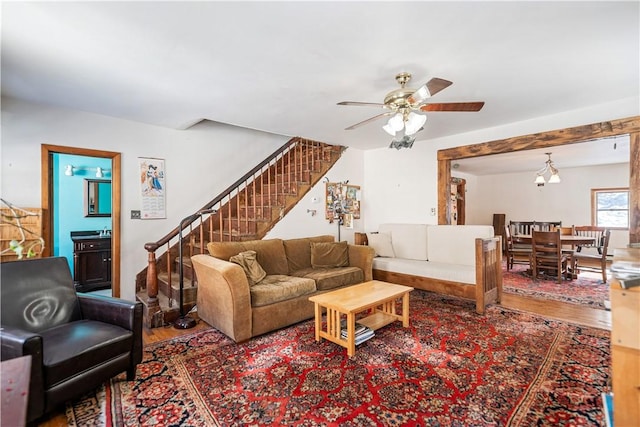 living area with stairs, a ceiling fan, and wood finished floors