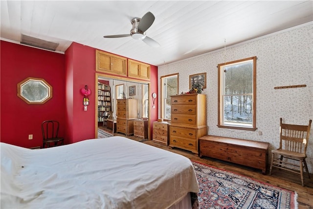 bedroom with wallpapered walls, a ceiling fan, and wood finished floors