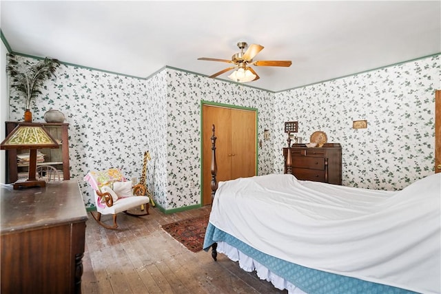 bedroom with hardwood / wood-style floors, a ceiling fan, and wallpapered walls