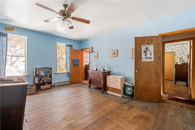 bedroom with multiple windows, hardwood / wood-style floors, ceiling fan, and a baseboard radiator