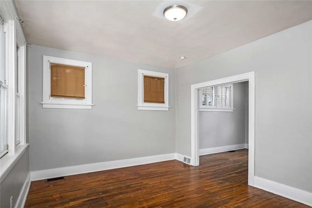 unfurnished room with visible vents, baseboards, and hardwood / wood-style floors