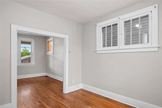 unfurnished room with baseboards and dark wood-type flooring